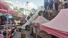 囧！女司机倒车时太紧张 皮卡车“挂”在菜市场